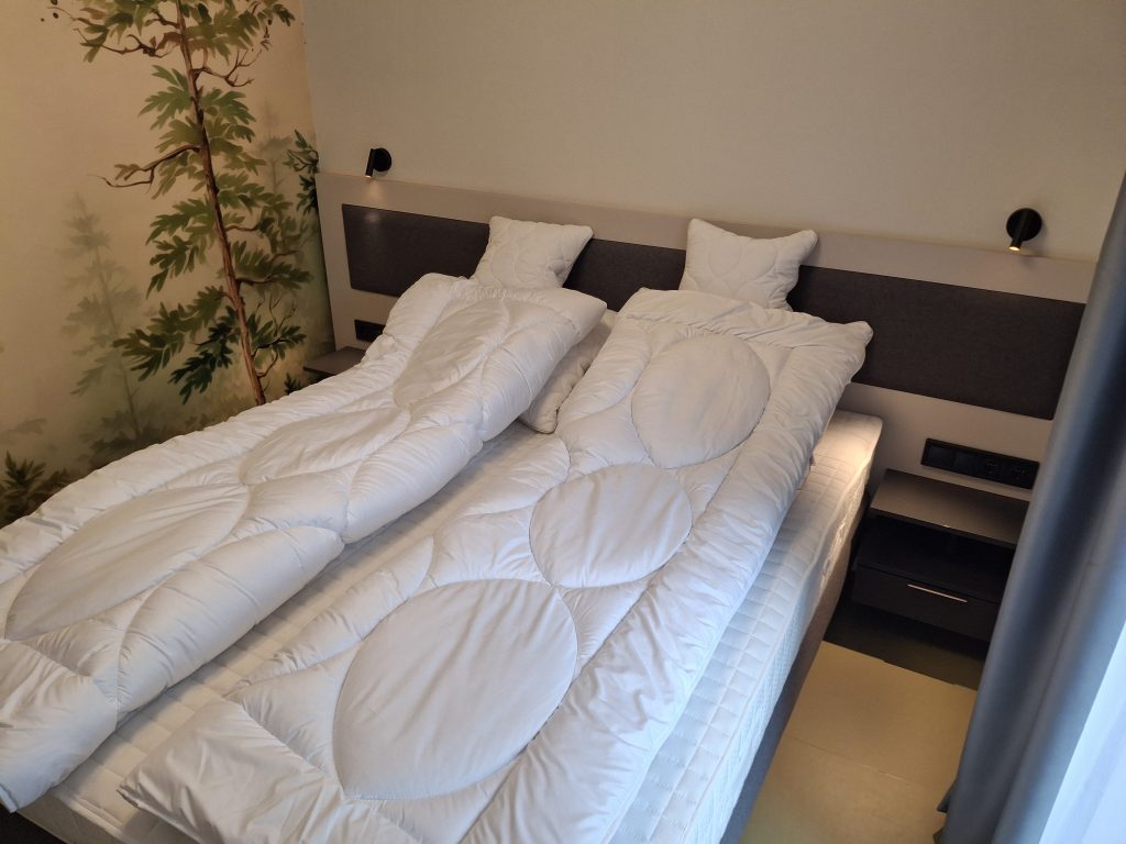 Hálószoba ággyal és éjjeliszekrénnyel a négyszemélyes apartmanban
