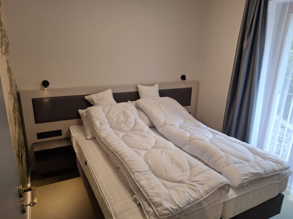 Hálószoba ággyal és éjjeliszekrénnyel a négyszemélyes apartmanban